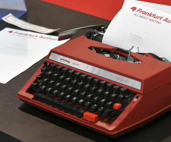 a red typewriter is shown with a sheet of typing paper inserted
