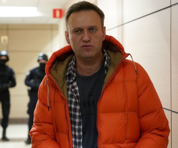 Alexei Navalny stands near law enforcement agents in a hallway of a business center.