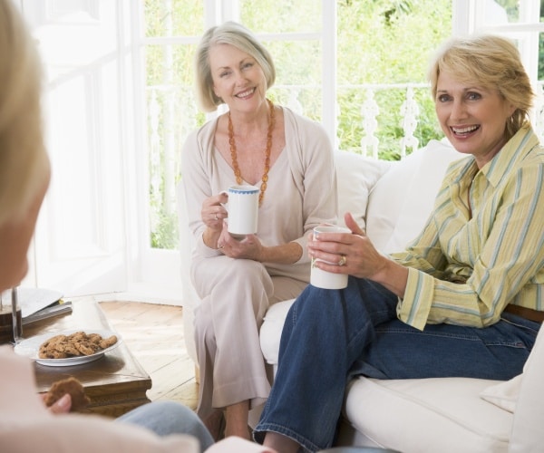 older women sitting on couch and drinking tea