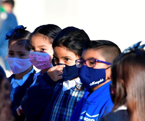 children lined up outside wearing masks