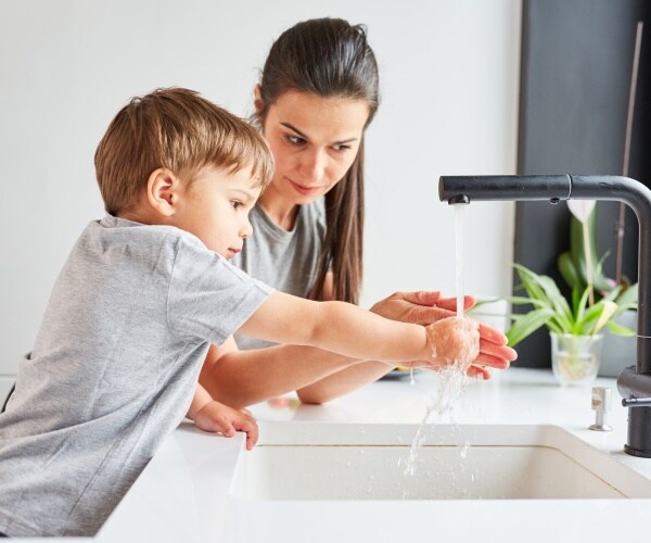 mother showing a child how to wash his hands