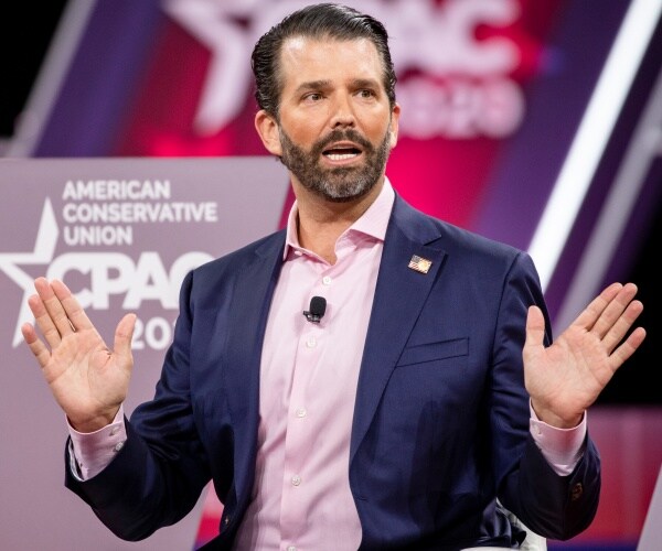 don jr in a suit and light pink shirt speaking at cpac