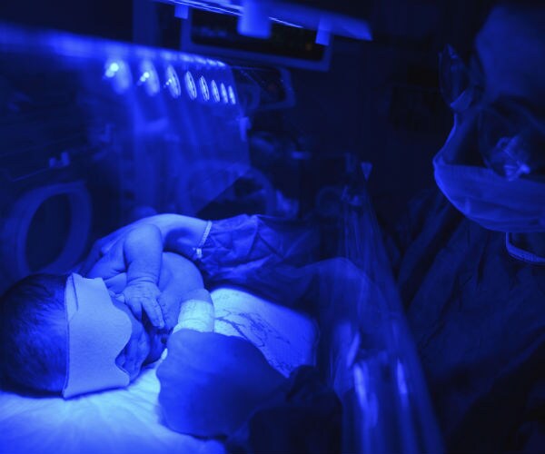 a baby boy is seen under a blue uv light