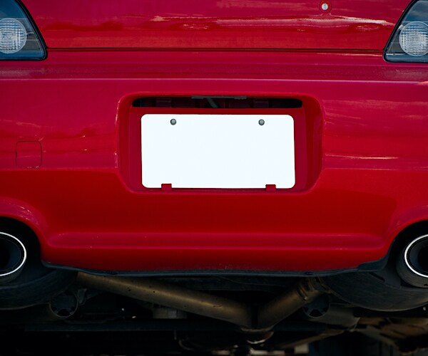 blank white license plate on rear of red car