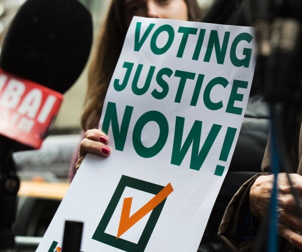 woman holds voting justice now sign 