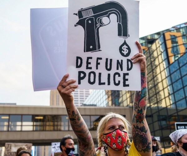 protester holding sign that says defund the police