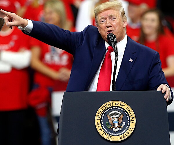 donald trump points to his right during a campaign rally among a see of red maga supporters
