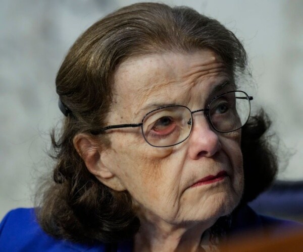 closeup of senator dianne feinstein in purple outfit with glasses and red lipstick