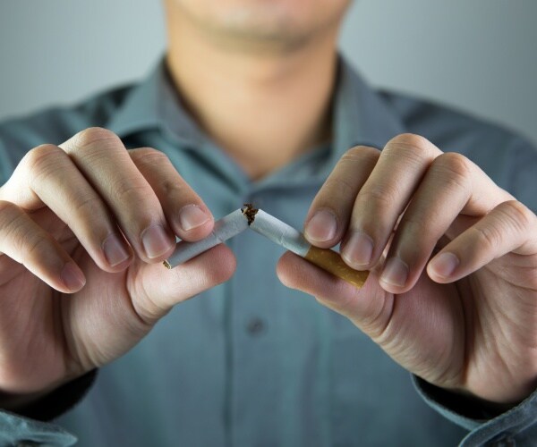 man breaking a cigarette in half