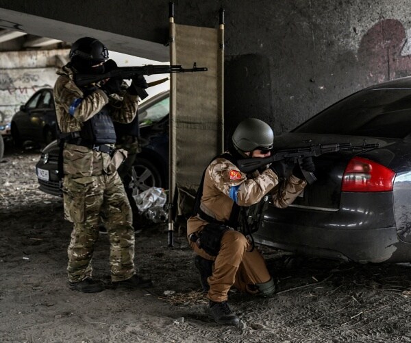 Ukrainian servicemen aim with their weapons at a moving car