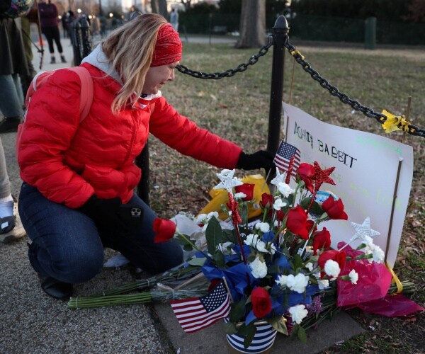 a woman cries at a memorial to ashli babbit