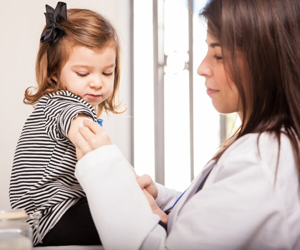 a doctor administers a flu shot to a young girl