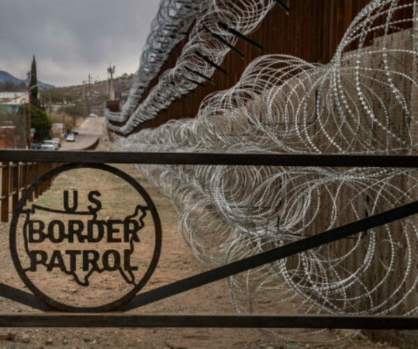 border patrol logo on a gate next to a razor wire fence
