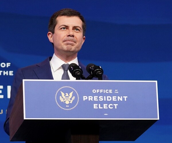 pete buttigieg stands behind podium