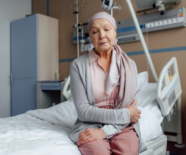older woman with cancer sitting on hospital bed