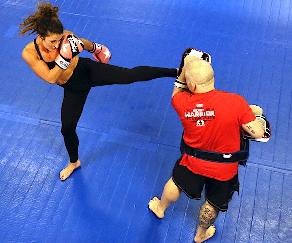 a woman kicks boxes with her personal trainer