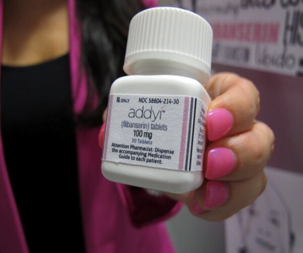 woman holding a bottle of Addyi pills
