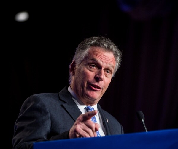 mcauliffe in a suit and blue tie speaking at a podium