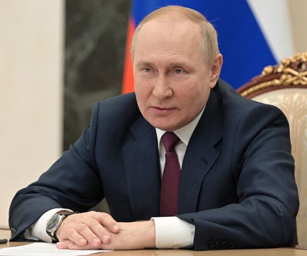 vladimir putin sits at a desk