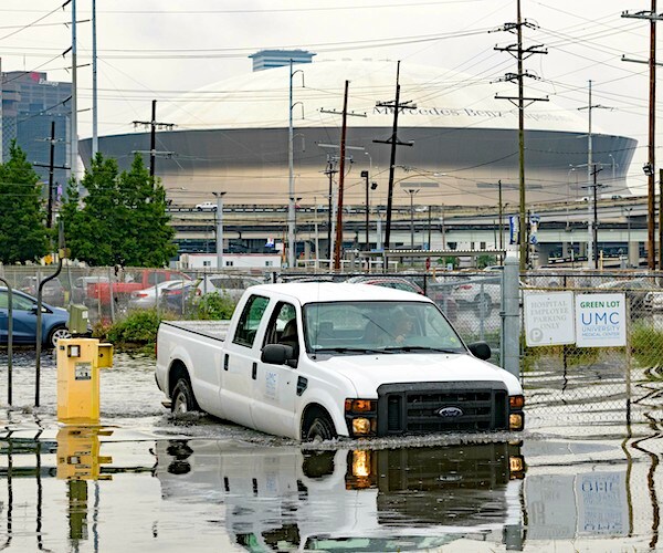 a truck drives through flood waters in new orleans with the superdome in the background