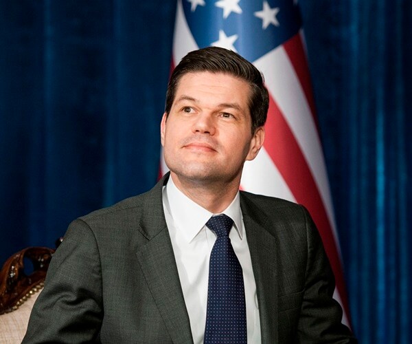 wess mitchell sticks his chin up and tilts the top of his head back while listen
